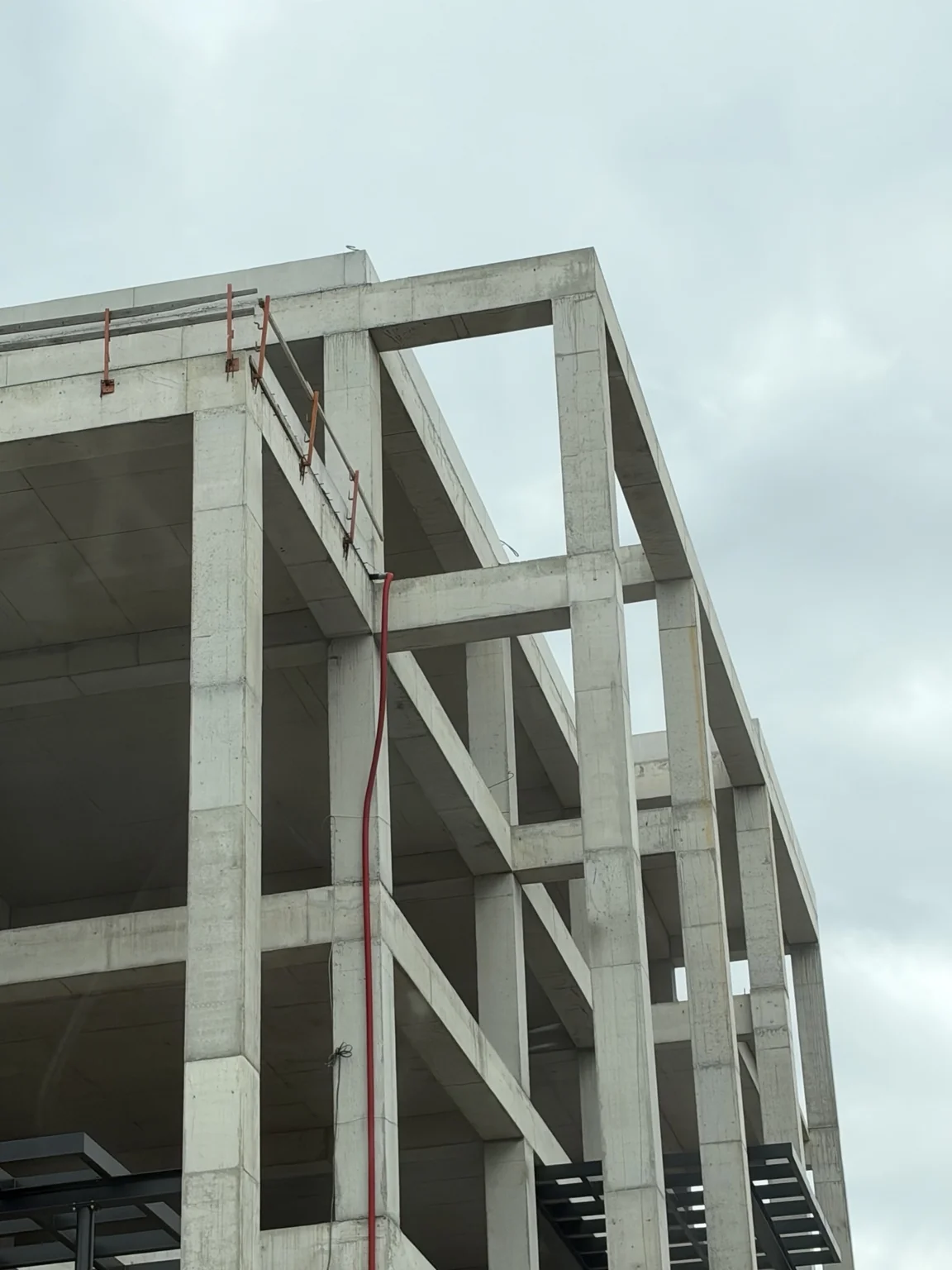 Exposed concrete building frame with columns, beams and floor slabs under construction