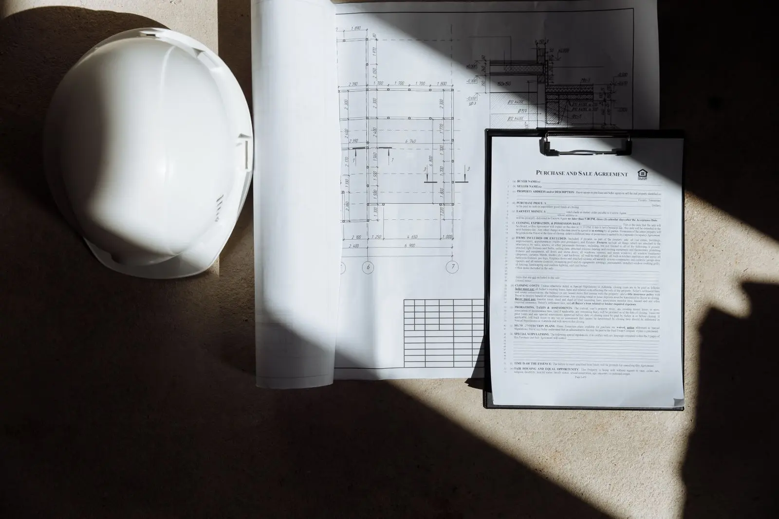 Real photograph of construction plans, project documents and a safety helmet