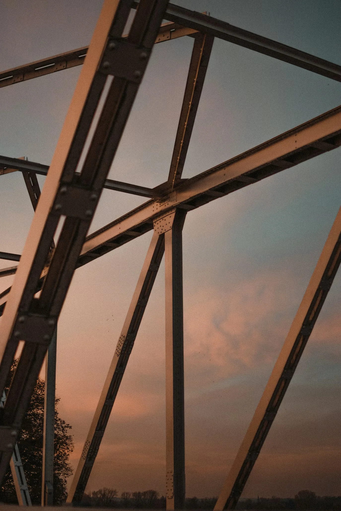 Steel frame with diagonal bracing and bolted connections against an evening sky